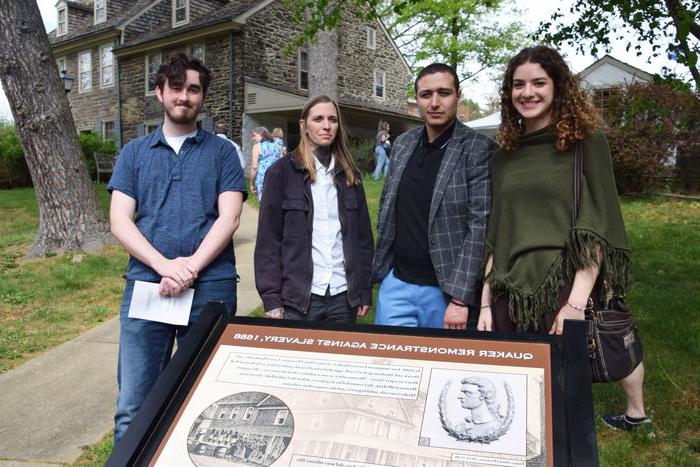 4 public history students standing in front of sign 