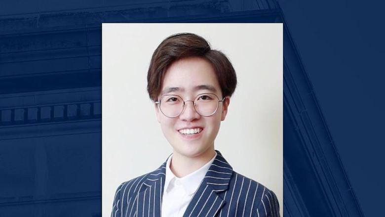 A headshot of a person wearing glasses on a blue background.